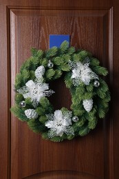 Beautiful Christmas wreath with festive decor hanging on wooden door