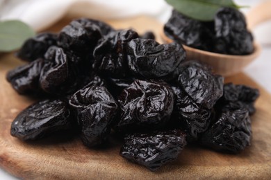 Photo of Tasty dried prunes on wooden board, closeup