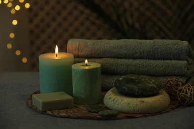 Photo of Spa composition. Burning candles, stones, soap and towels on grey table