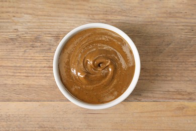 Delicious nut butter in bowl on wooden table, top view