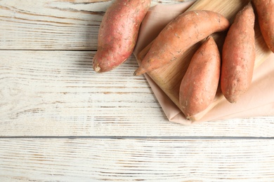 Photo of Flat lay composition with sweet potatoes and space for text on white wooden background