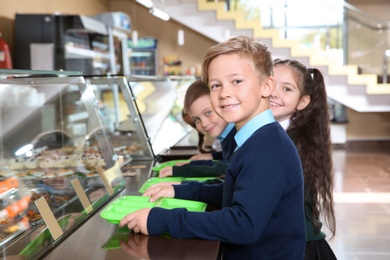 Photo of Children near serving line with healthy food in school canteen
