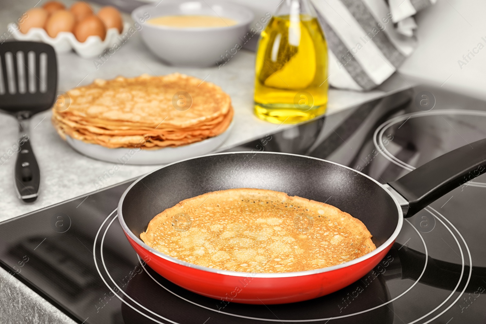 Photo of Delicious thin pancake in frying pan on induction stove, closeup