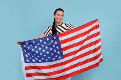 4th of July - Independence Day of USA. Happy woman with American flag on light blue background