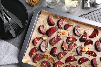 Baking tray with roasted beetroot slices on grey table, flat lay