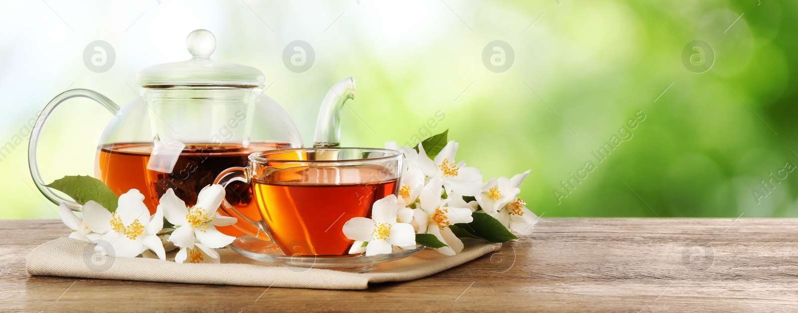 Image of Jasmine tea and fresh flowers on wooden table outdoors, space for text. Banner design