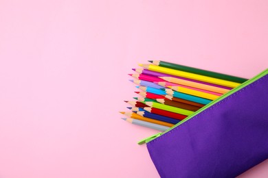 Photo of Many colorful pencils in pencil case on pink background, top view. Space for text