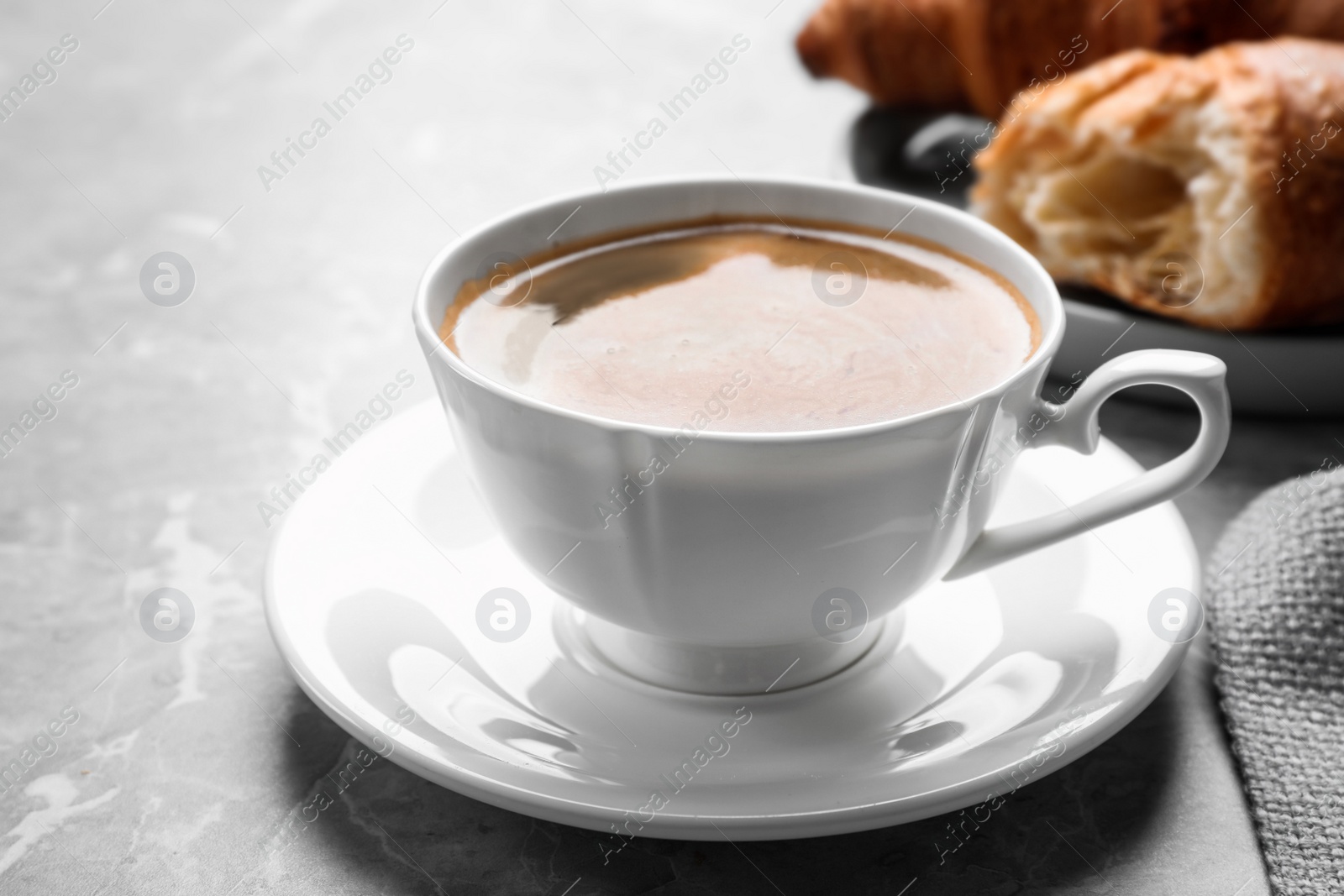 Photo of Coffee and tasty croissants on light grey marble table, closeup