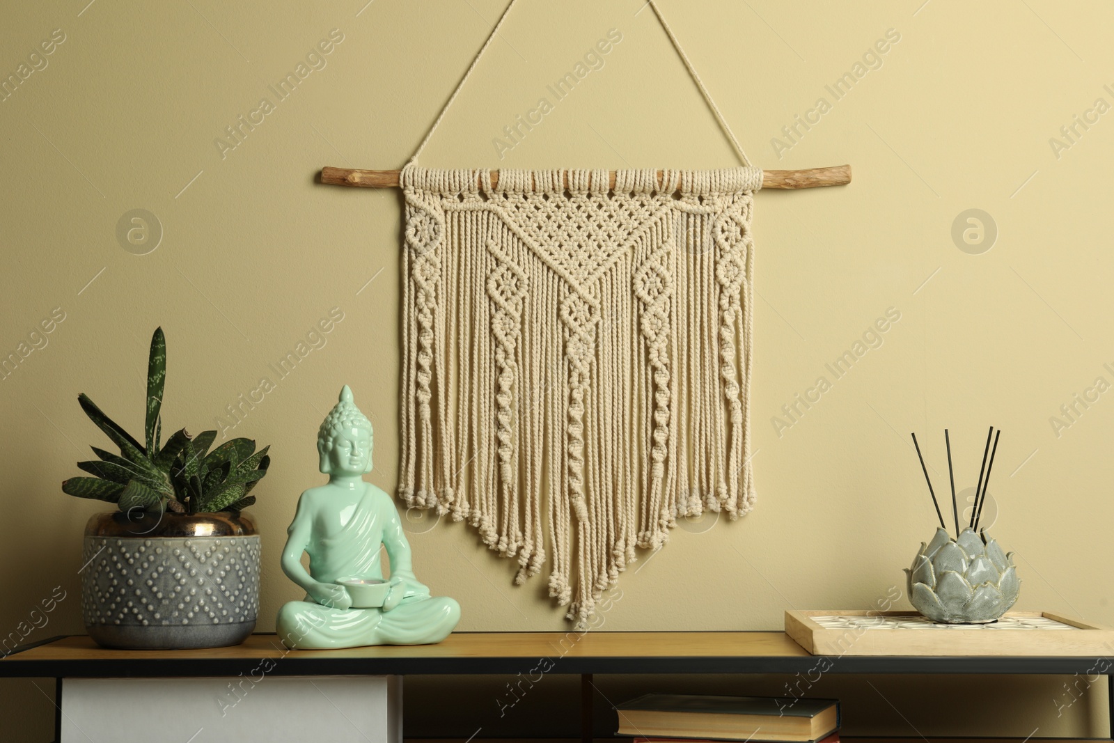 Photo of Beautiful macrame hanging on beige wall in room. Decorative element