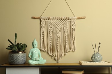 Photo of Beautiful macrame hanging on beige wall in room. Decorative element