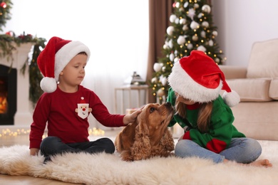 Photo of Cute little kids with English Cocker Spaniel in room decorated for Christmas
