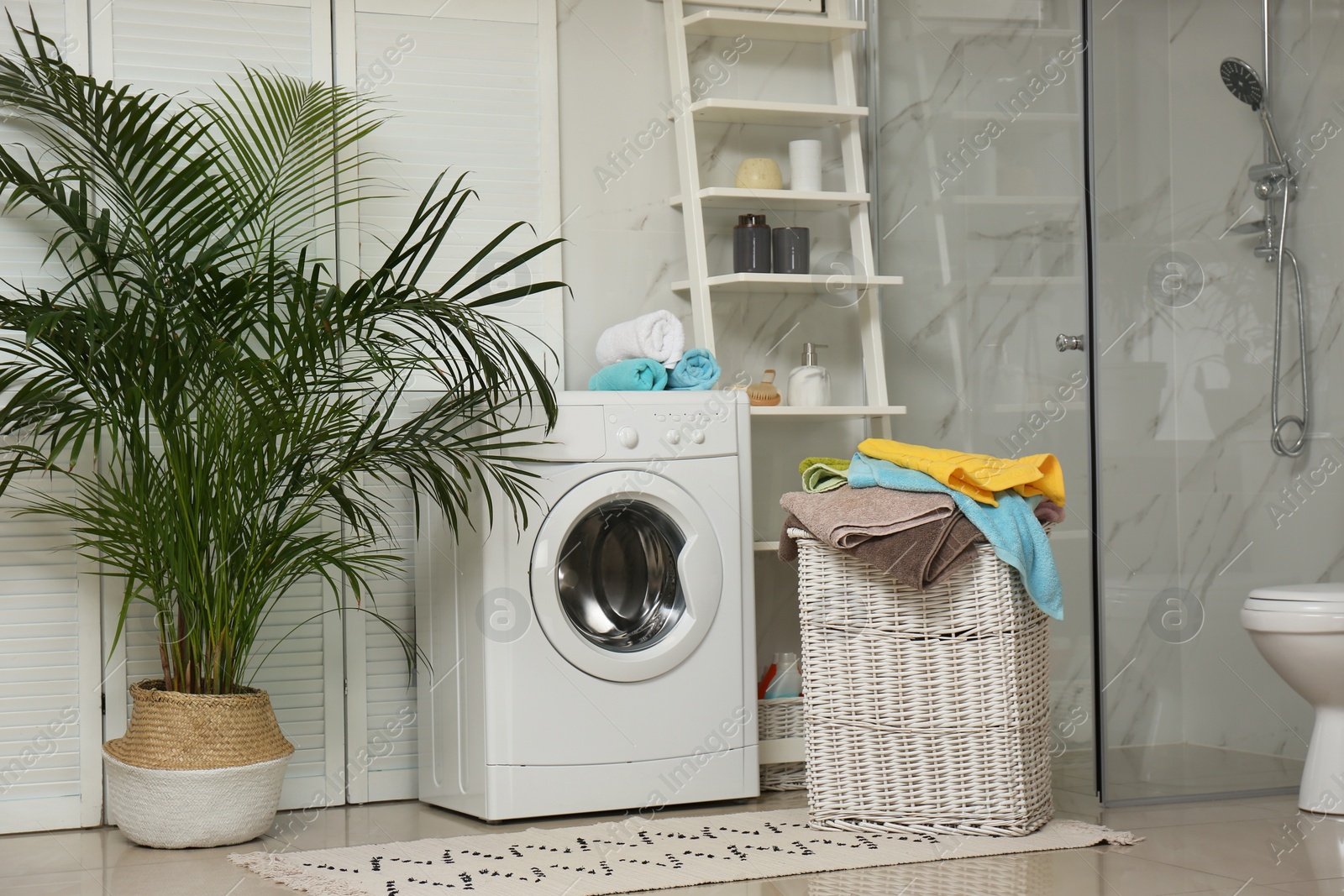 Photo of Wicker basket with laundry and washing machine in bathroom