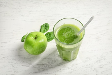 Glass with delicious detox juice and ingredients on light background