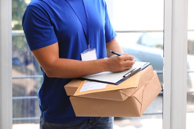 Photo of Young courier delivering parcels on doorstep, closeup