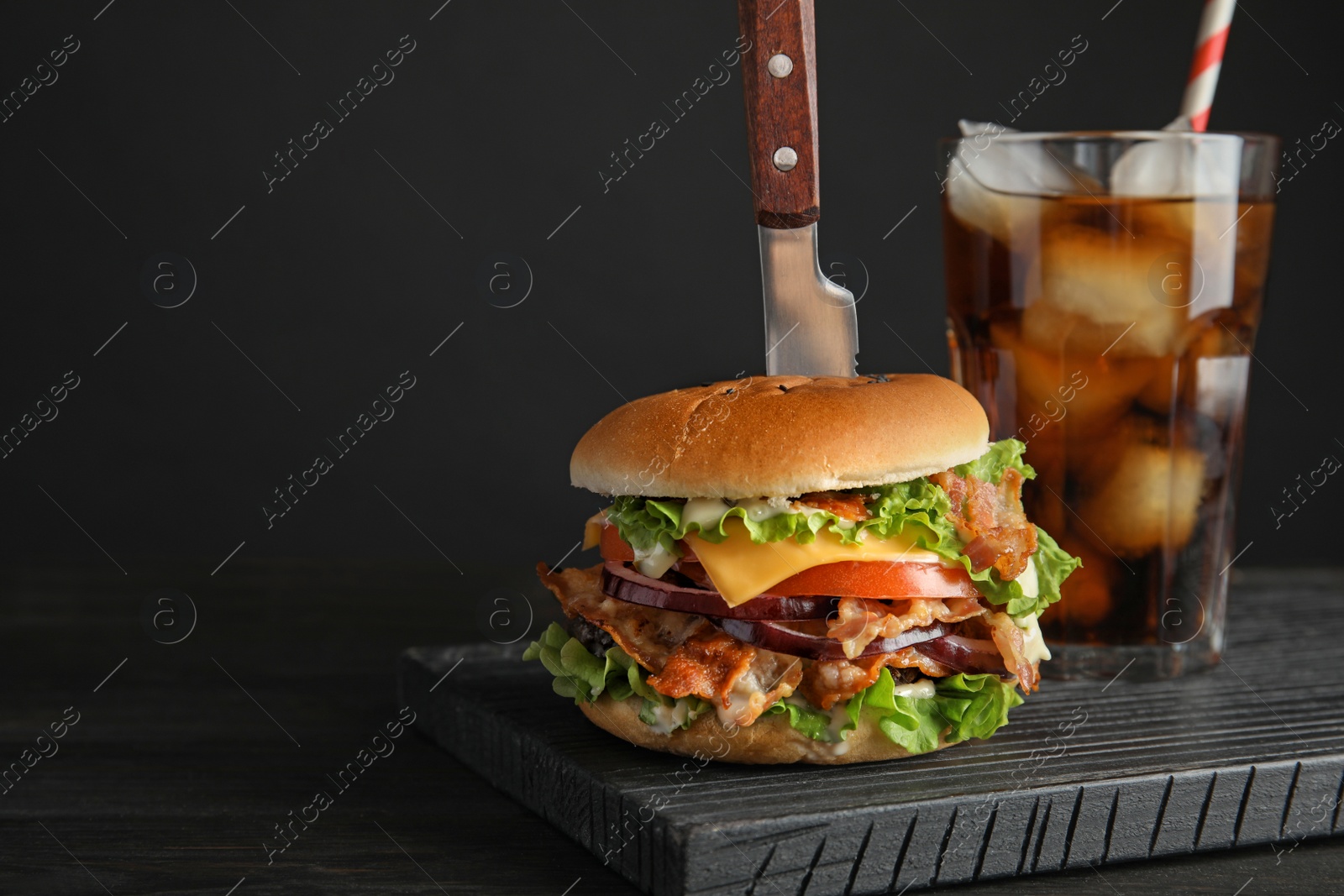 Photo of Tasty burger with bacon and cola on black background. Space for text