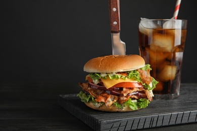 Photo of Tasty burger with bacon and cola on black background. Space for text
