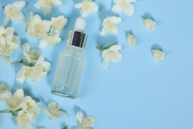 Photo of Essential oil in bottle and beautiful jasmine flowers on light blue background, flat lay. Space for text