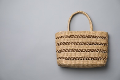Stylish straw bag on grey background, top view with space for text. Summer accessory
