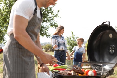 Happy family having barbecue with modern grill outdoors