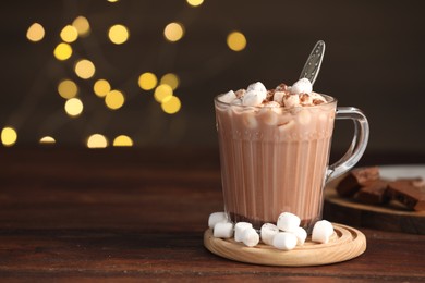 Photo of Cup of aromatic hot chocolate with marshmallows and cocoa powder on wooden table, space for text
