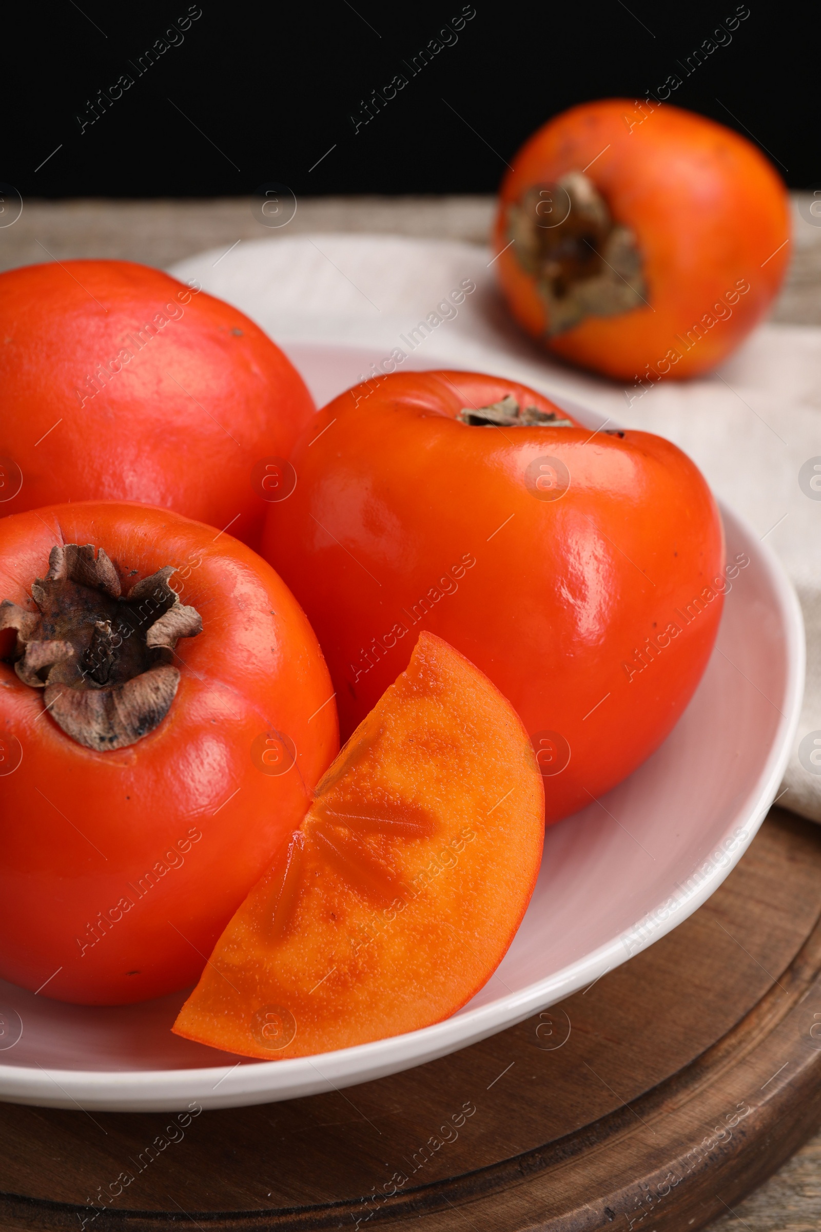 Photo of Delicious ripe persimmons on wooden board, closeup