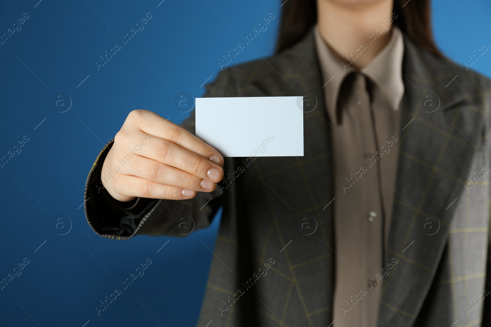 Photo of Woman holding white business card on blue background, closeup