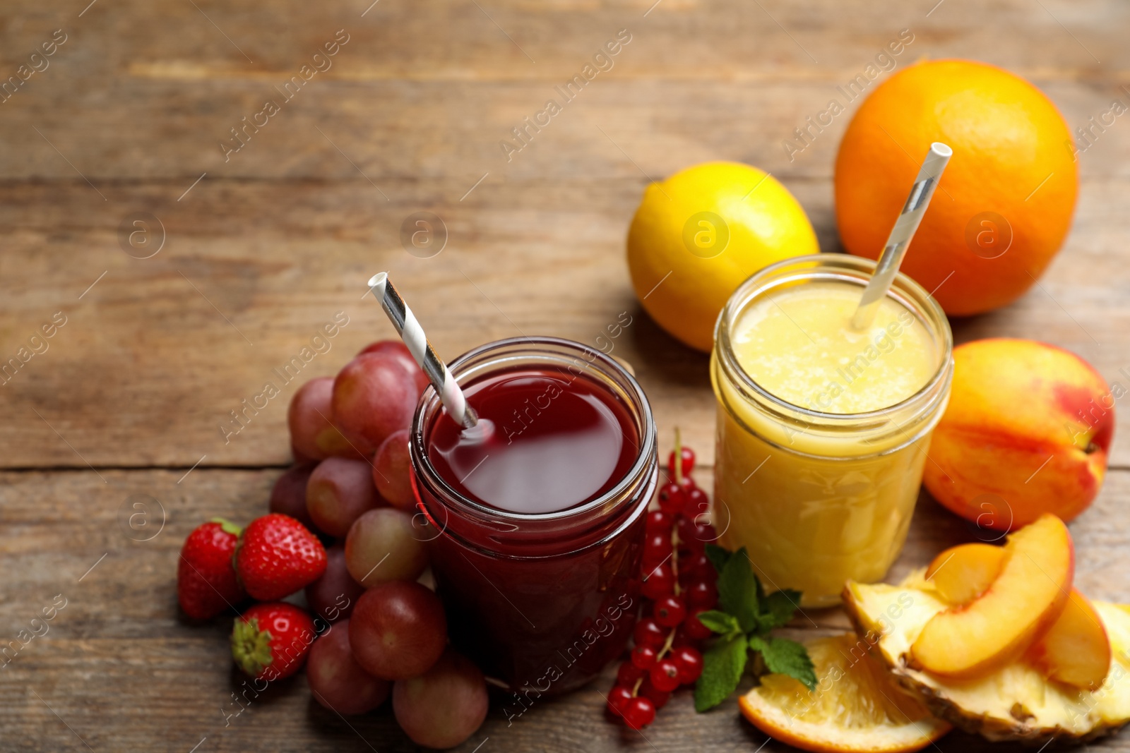 Photo of Delicious colorful juices in glasses and fresh ingredients on wooden table