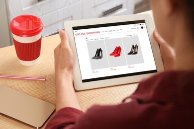 Woman shopping online via computer tablet at table, closeup