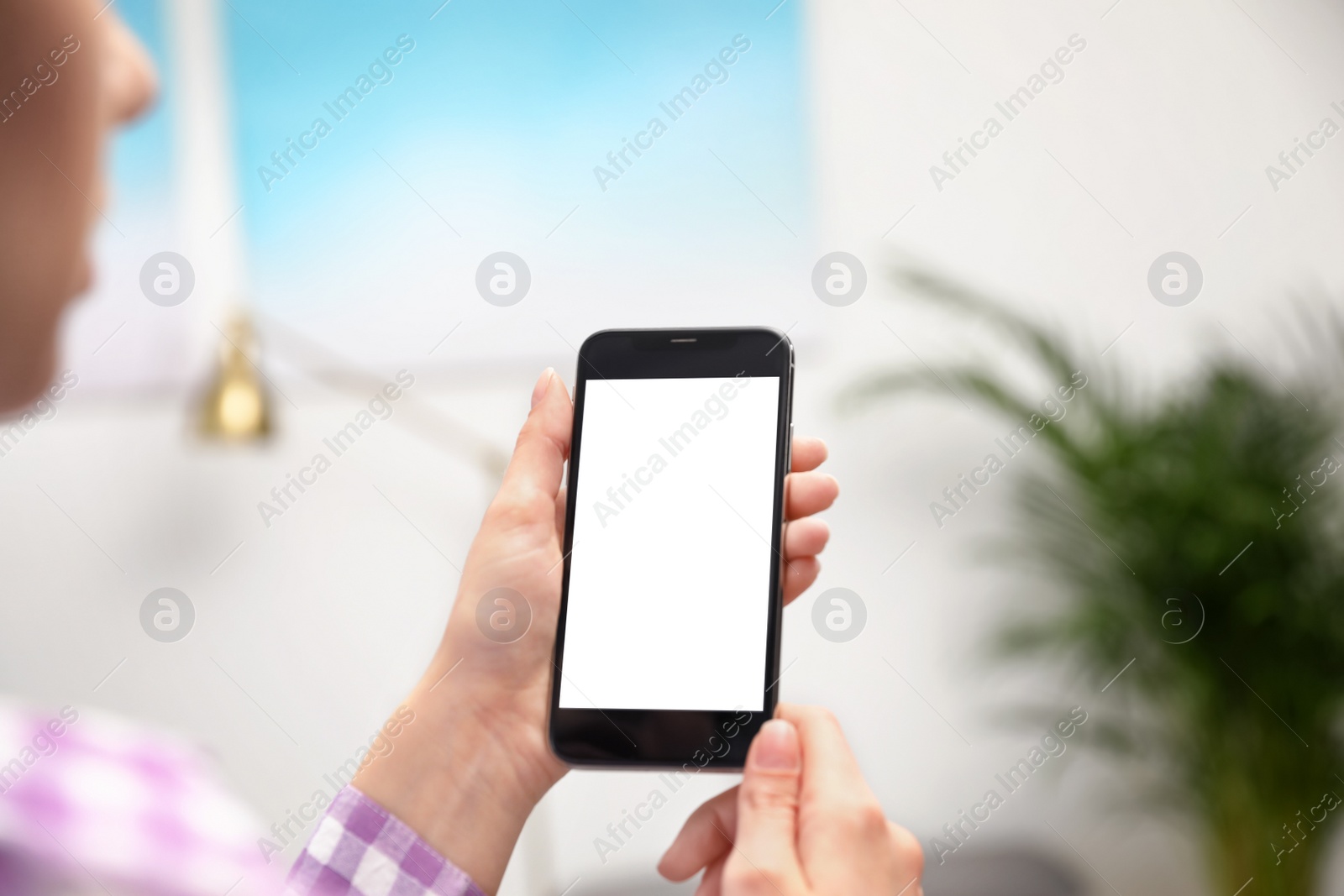 Photo of Woman holding smartphone with blank screen indoors, closeup of hands. Space for text