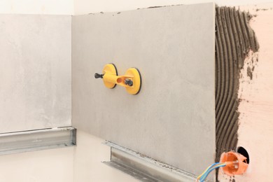 Photo of Yellow suction plate attached to tile on wall