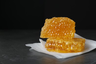 Natural honeycombs on dark table against black background, space for text