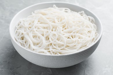 Bowl with cooked rice noodles on light marble table, closeup