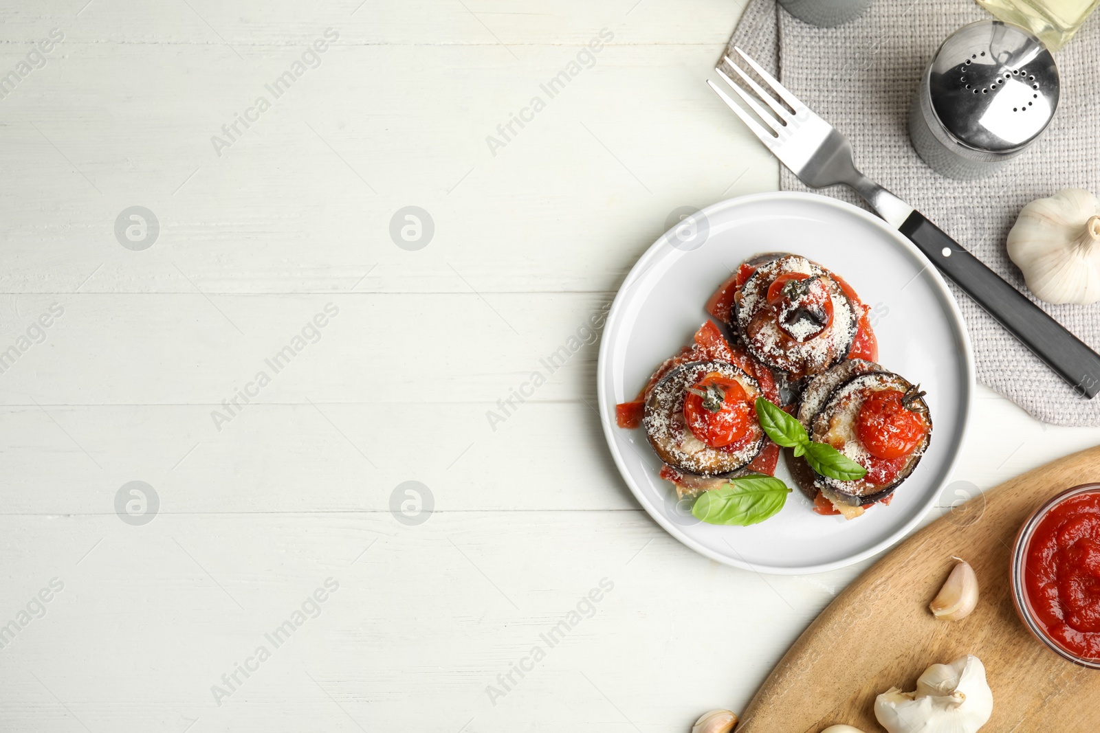 Photo of Baked eggplant with tomatoes, cheese and basil served on white wooden table, flat lay. Space for text