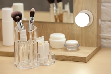 Photo of Organizer with cosmetic products and makeup accessories on dressing table indoors