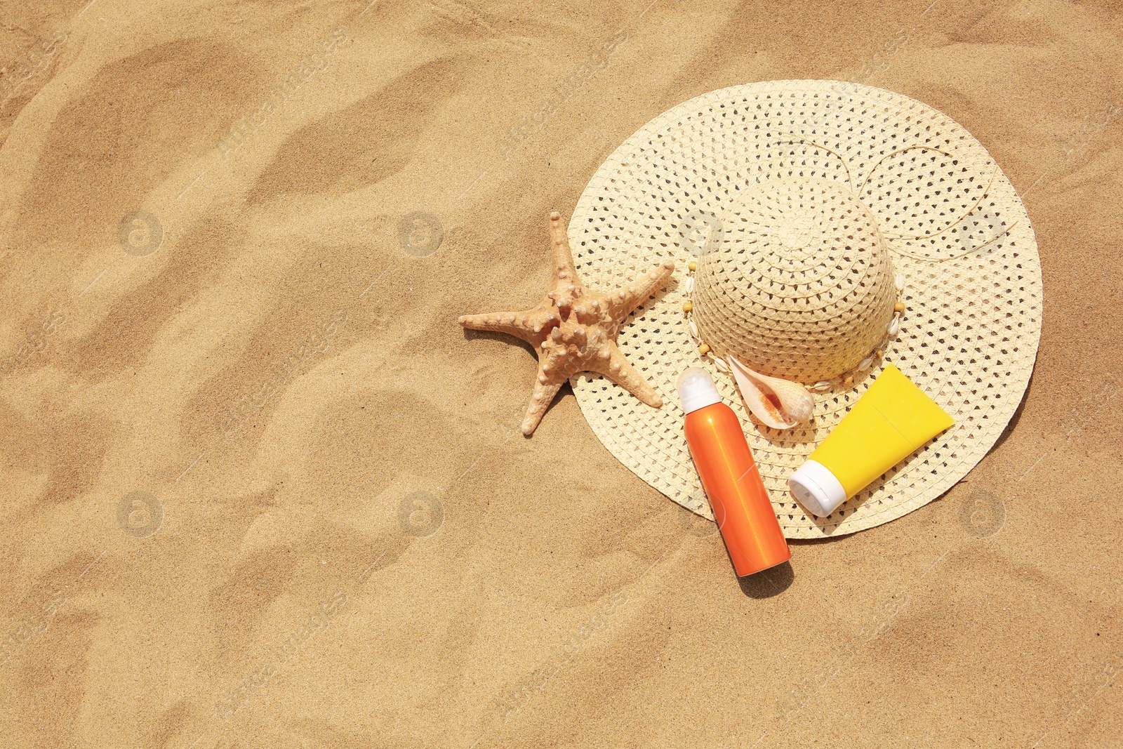 Photo of Flat lay composition with sunscreens on sand, space for text. Sun protection care