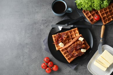 Tasty Belgian waffles served with bacon, butter and coffee on grey table, flat lay. Space for text