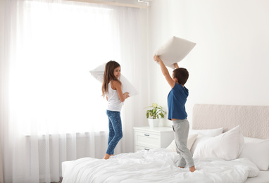 Happy children having pillow fight in bedroom