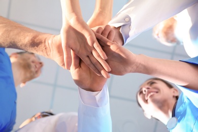 Young medical doctors putting hands together indoors, bottom view. Unity concept