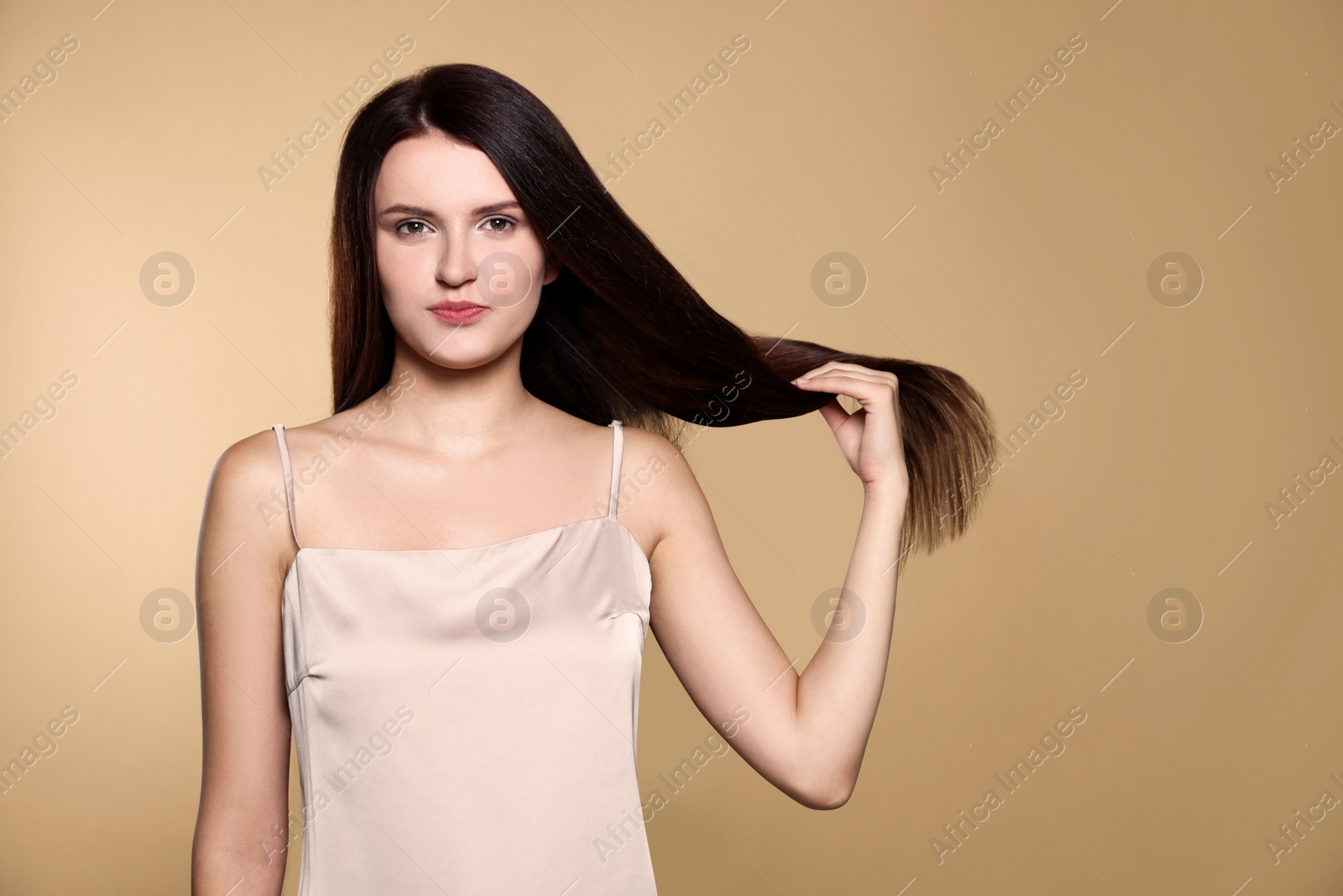 Photo of Portrait of beautiful young woman with healthy strong hair on beige background