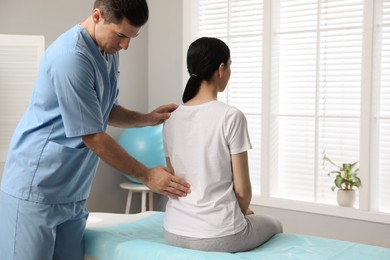 Orthopedist examining woman's back in clinic. Scoliosis treatment