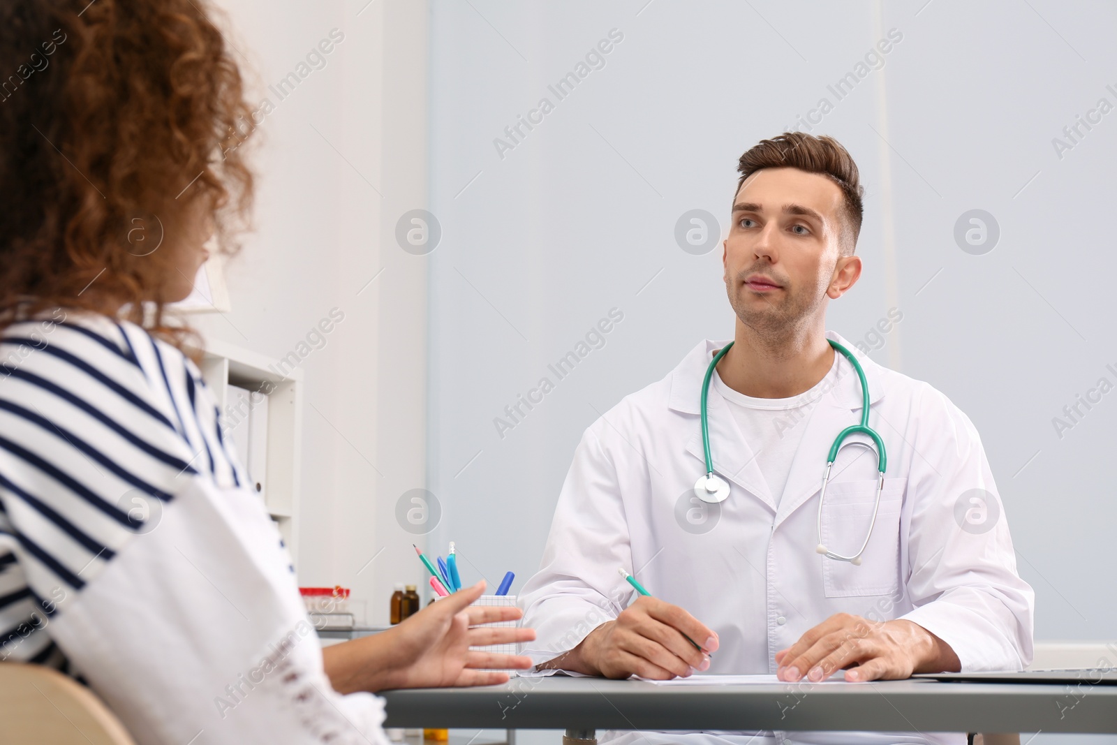 Photo of Male doctor working with African American patient in hospital