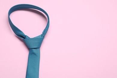 Photo of Blue necktie on pink background, above view. Space for text