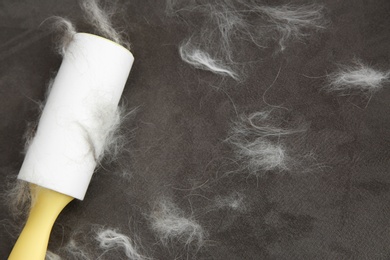 Photo of Modern lint roller and cat hair on brown fabric, closeup