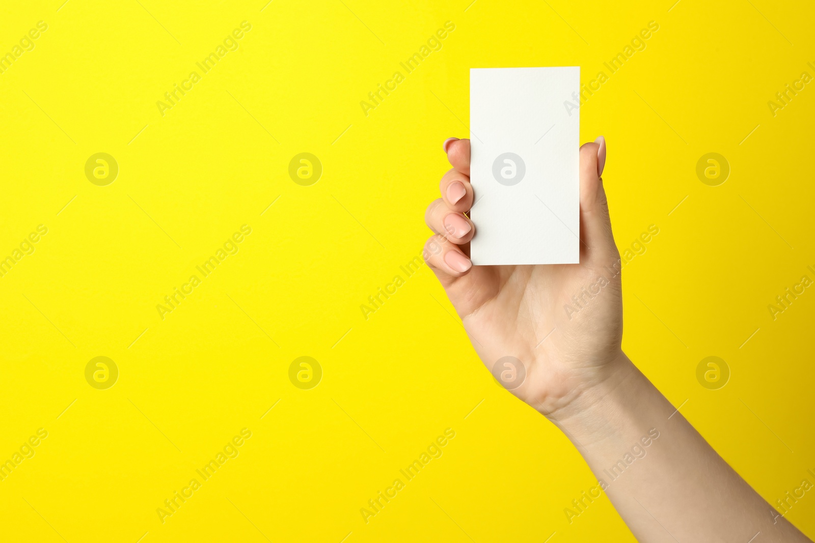 Photo of Woman holding blank business card on yellow background, closeup. Mockup for design