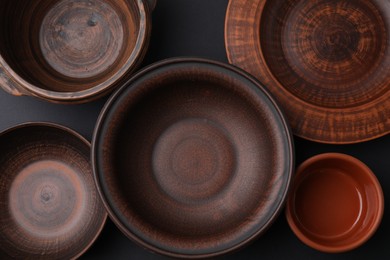 Photo of Bowls and plates on black background, flat lay