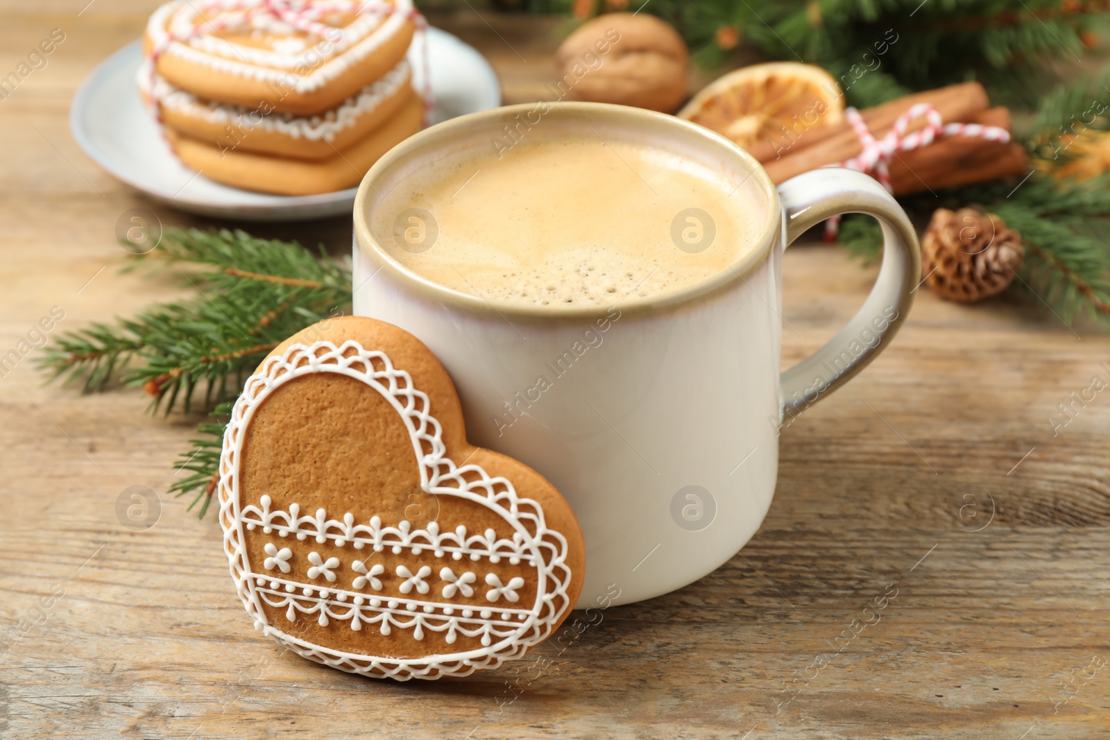 Photo of Tasty heart shaped gingerbread cookie and hot drink on wooden table