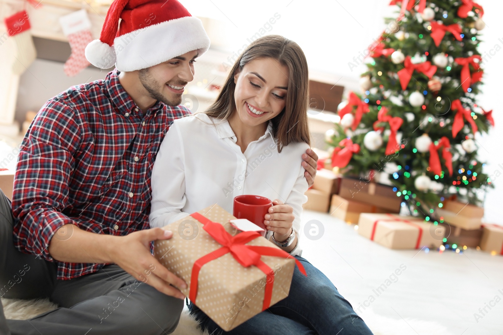 Photo of Young couple with Christmas gift at home