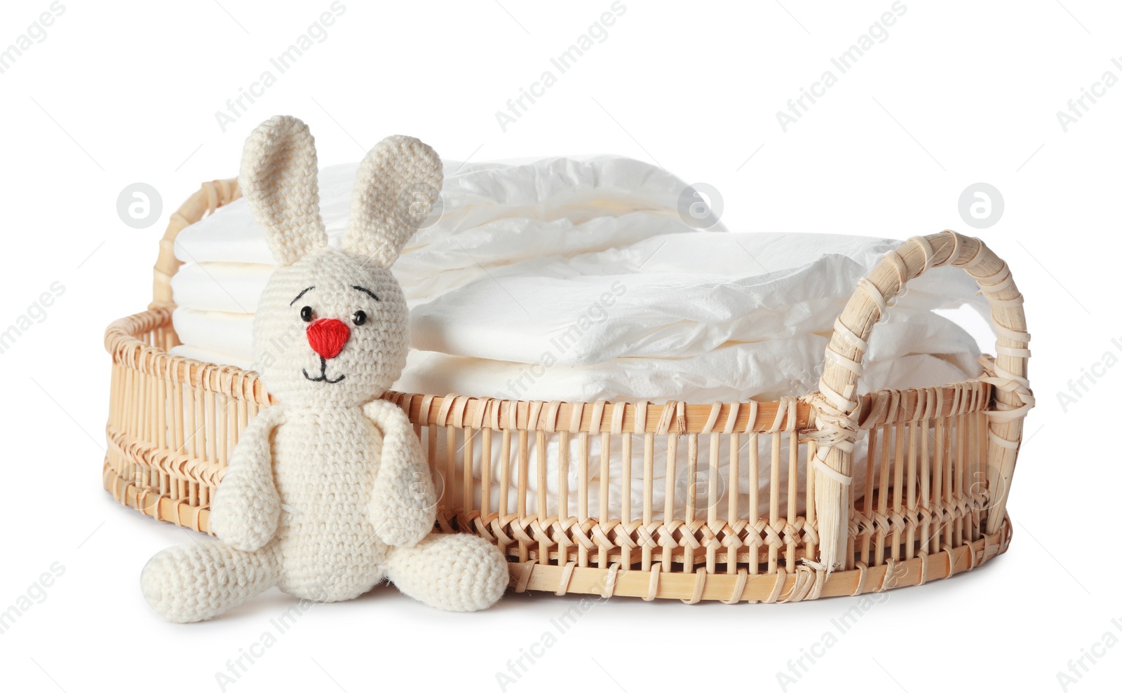 Photo of Wicker tray with disposable diapers and toy bunny on white background