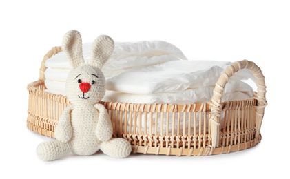 Wicker tray with disposable diapers and toy bunny on white background