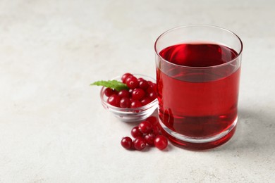 Photo of Tasty refreshing cranberry juice, mint and fresh berries on light table. Space for text